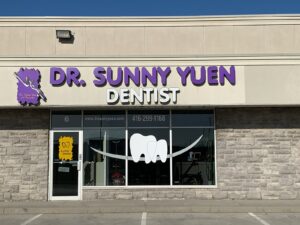 Exterior view of Dr. Sunny Yuen Dentist clinic featuring bold purple and white signage above the entrance and a tooth graphic on the front window
